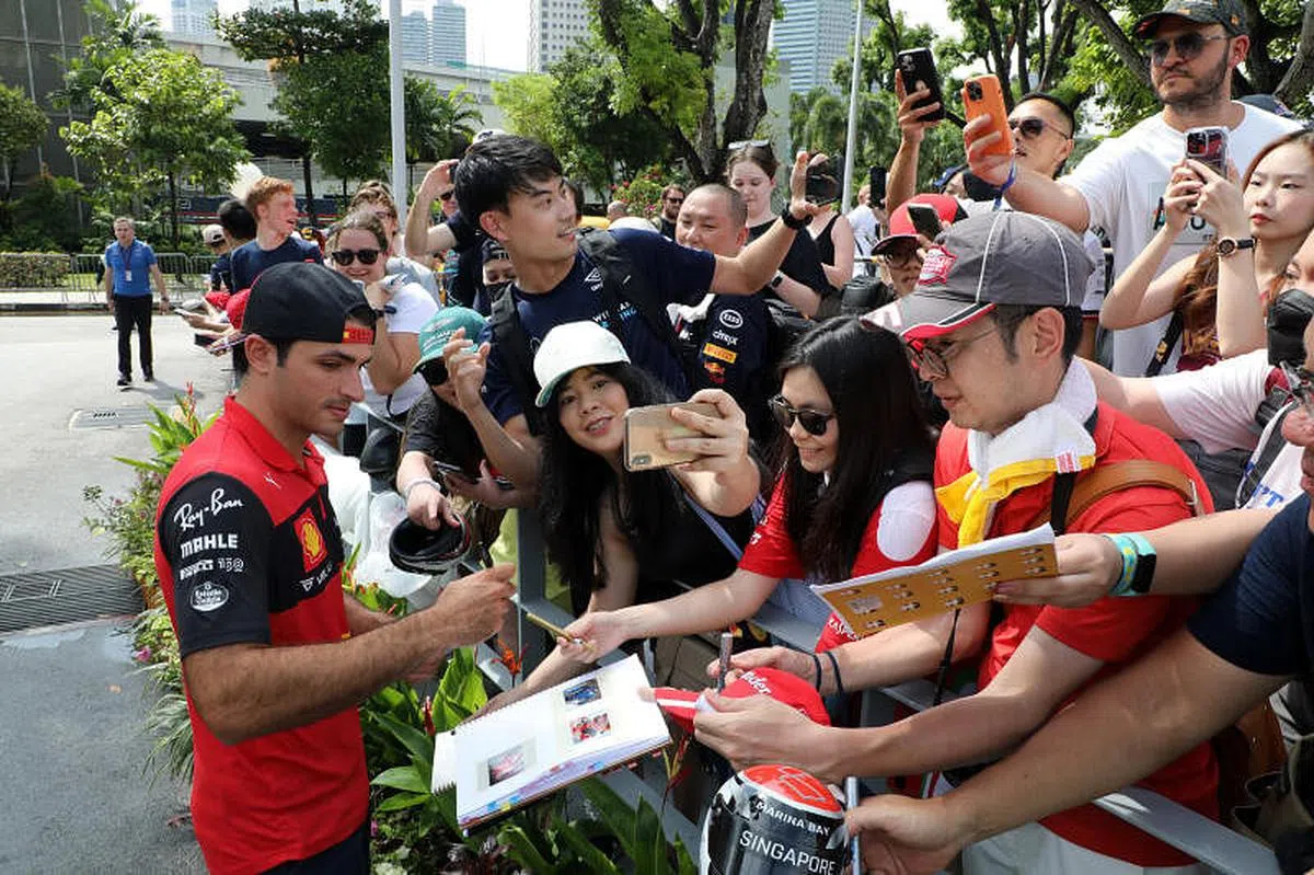 车迷们在雨后聚集在场外，等到法拉利车手塞恩斯为他们签名。（邝启聪摄）