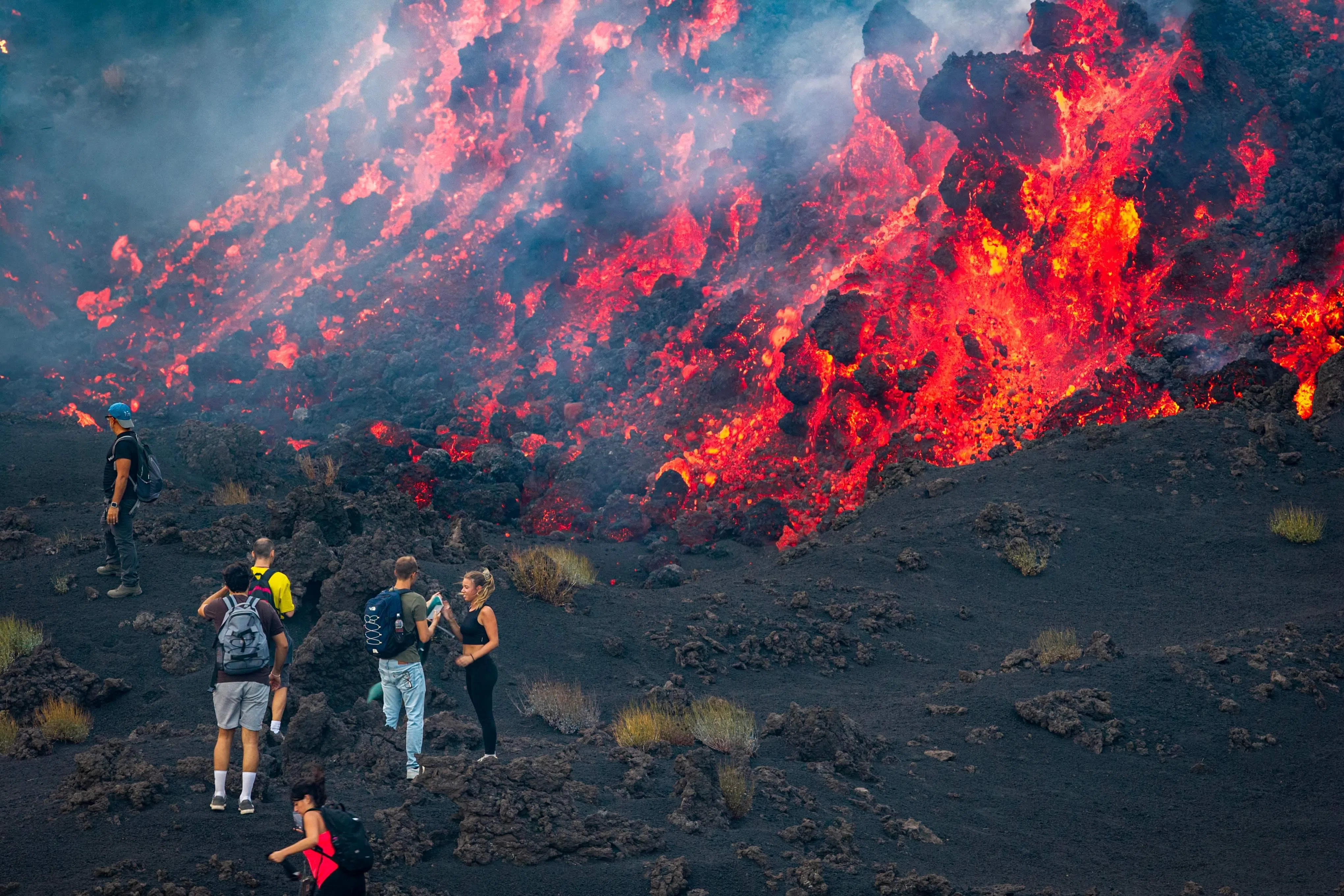 8月11日拍摄的照片显示，一些游客们站在埃特纳火山喷发时流出的​​熔岩旁边。（法新社）