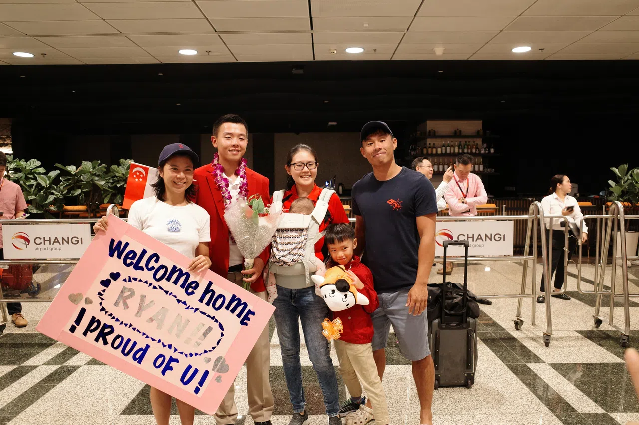 卢军汉（左二）与家人和朋友一同合影，海报写着“欢迎回家，我们为你自豪。”（卓舒畅摄）