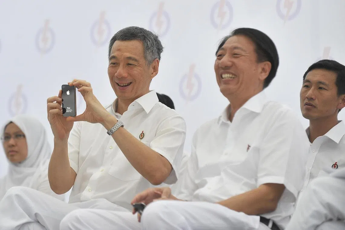 张志贤（右二）是李总理（左二）20年任期当中，出任副手时间最长的一位，堪称李总理的左膀右臂。图为2011年5月3日全国大选期间，人民行动党在市中心举行竞选群众大会时，李总理掏出手机拍照的情况。在台上的还有首次参加大选的殷丹博士（左一）与王乙康（右一）。（档案照片）