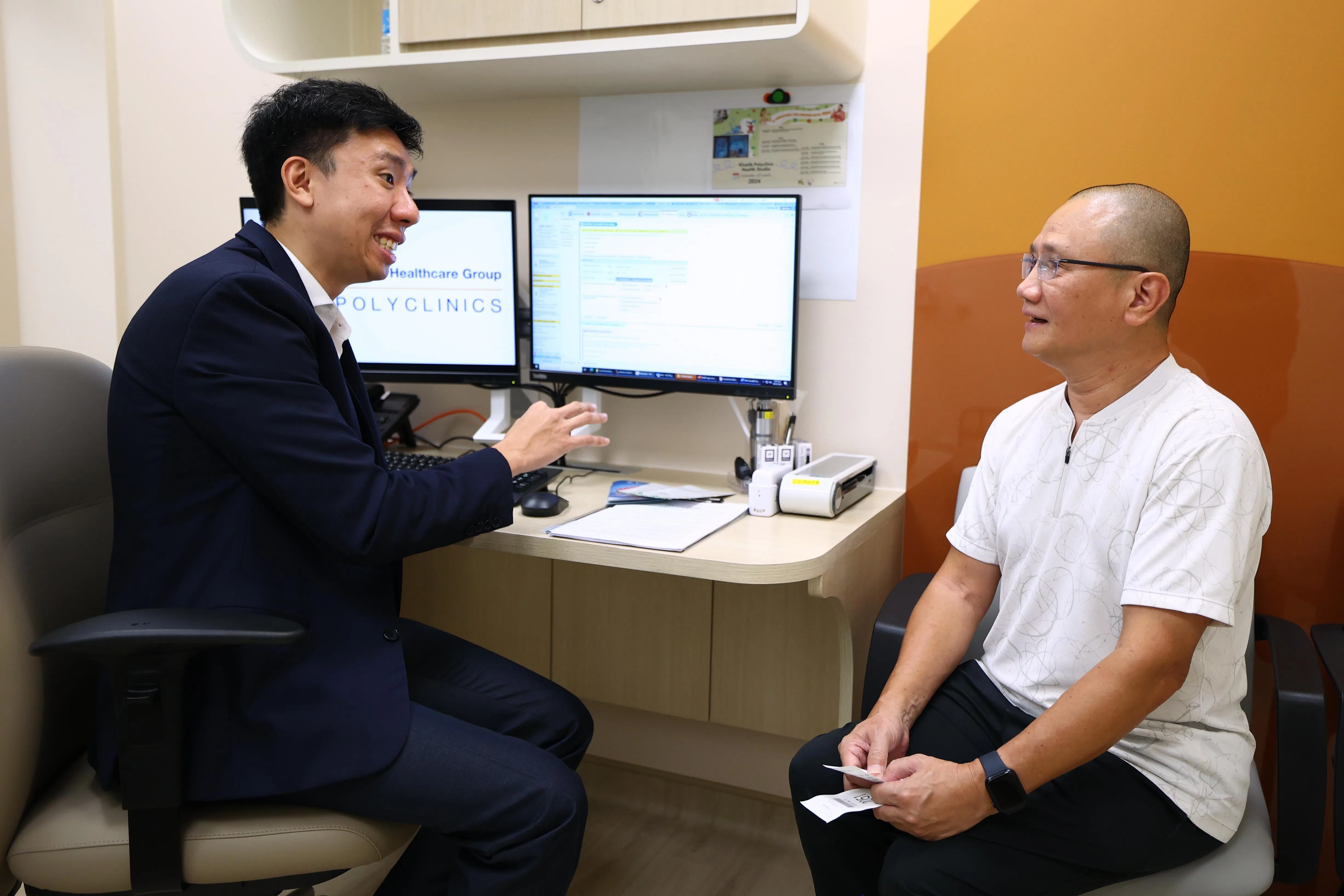 卡迪综合诊疗所副主管施凯平医生（左）向患者王瑞兴推荐社区里的锻炼活动，不仅帮助他管理高胆固醇的情况，还鼓励他养成健康的运动习惯。（林明顺摄）