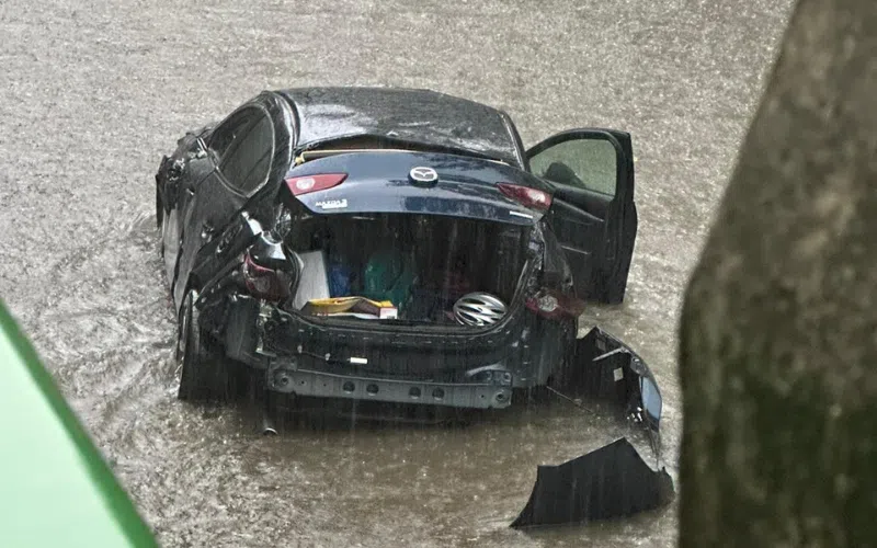 汽车打滑掉入沟渠后下起大雨，车身被浸在湍急的流水中。（读者提供）