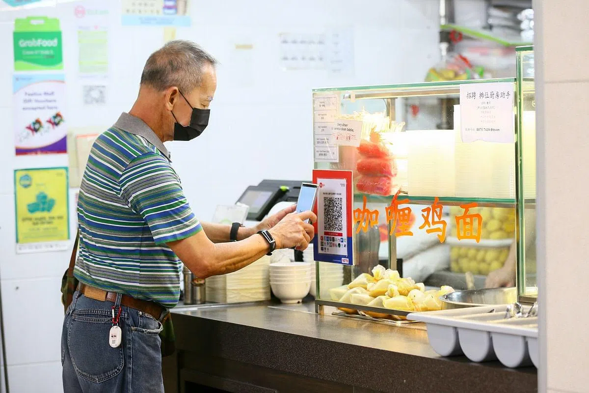 72岁的陈美豹学会使用手机进行电子付费后，到小贩中心用餐都会尽量使用这个方式付款，不必担心身上不够现金，也更方便。（施策文摄）