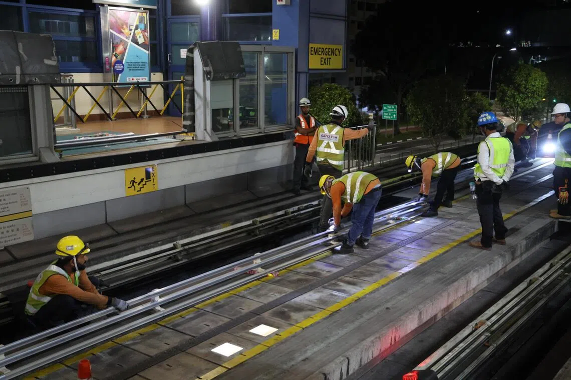 供电轨由五根平行安装的铝条组成。工作人员在月台旁的轨道上组装，再由六人抬送这个重达120公斤的新供电轨，到施工地点。（唐家鸿摄）