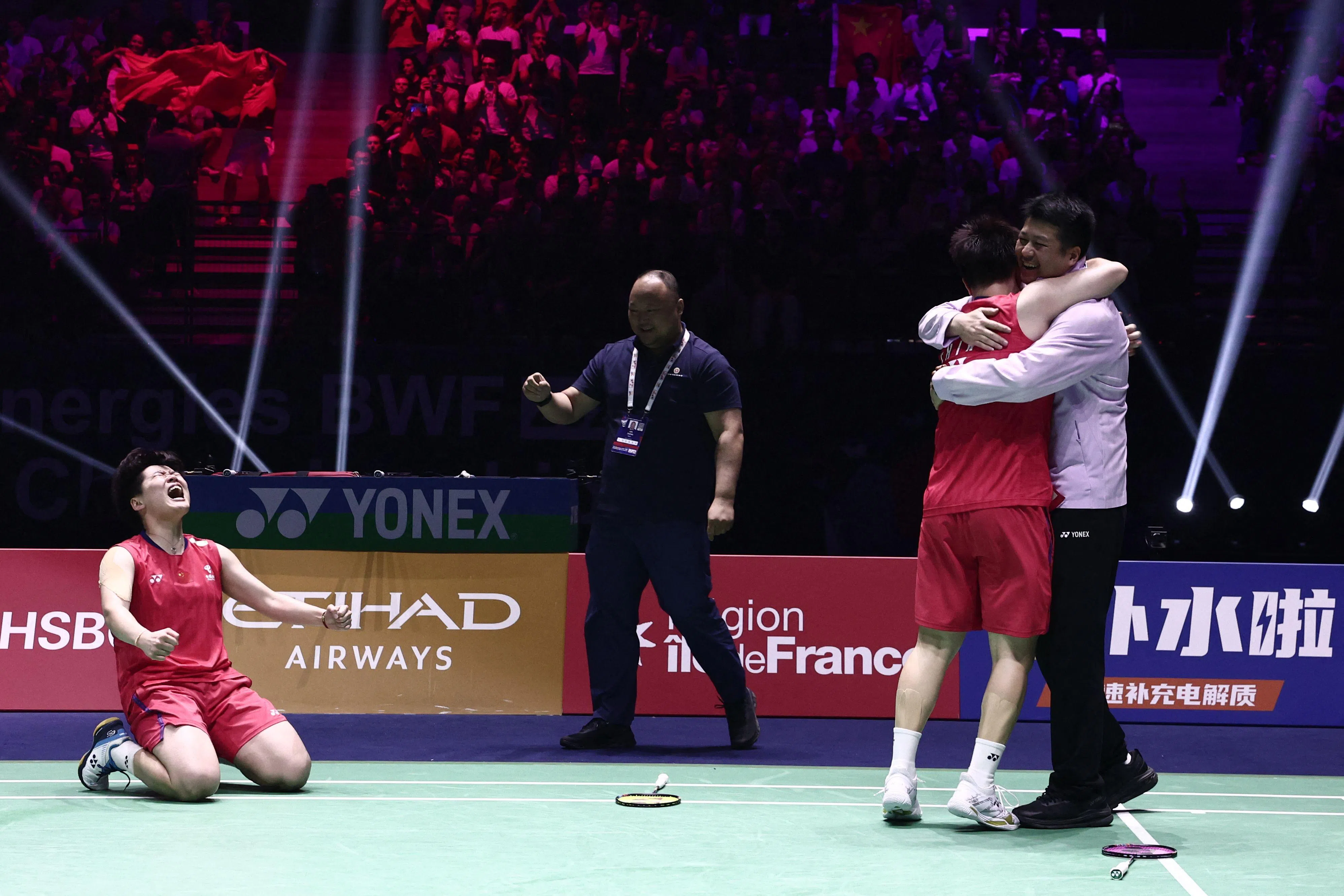 谭宁（左）在夺冠后激动跪地握拳庆祝，刘圣书（右二）则紧紧拥抱教练。（法新社）