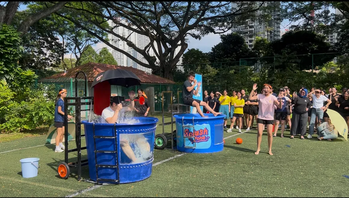 两位老师参与水上嘉年华的投球落水桶游戏。（叶小娴摄）