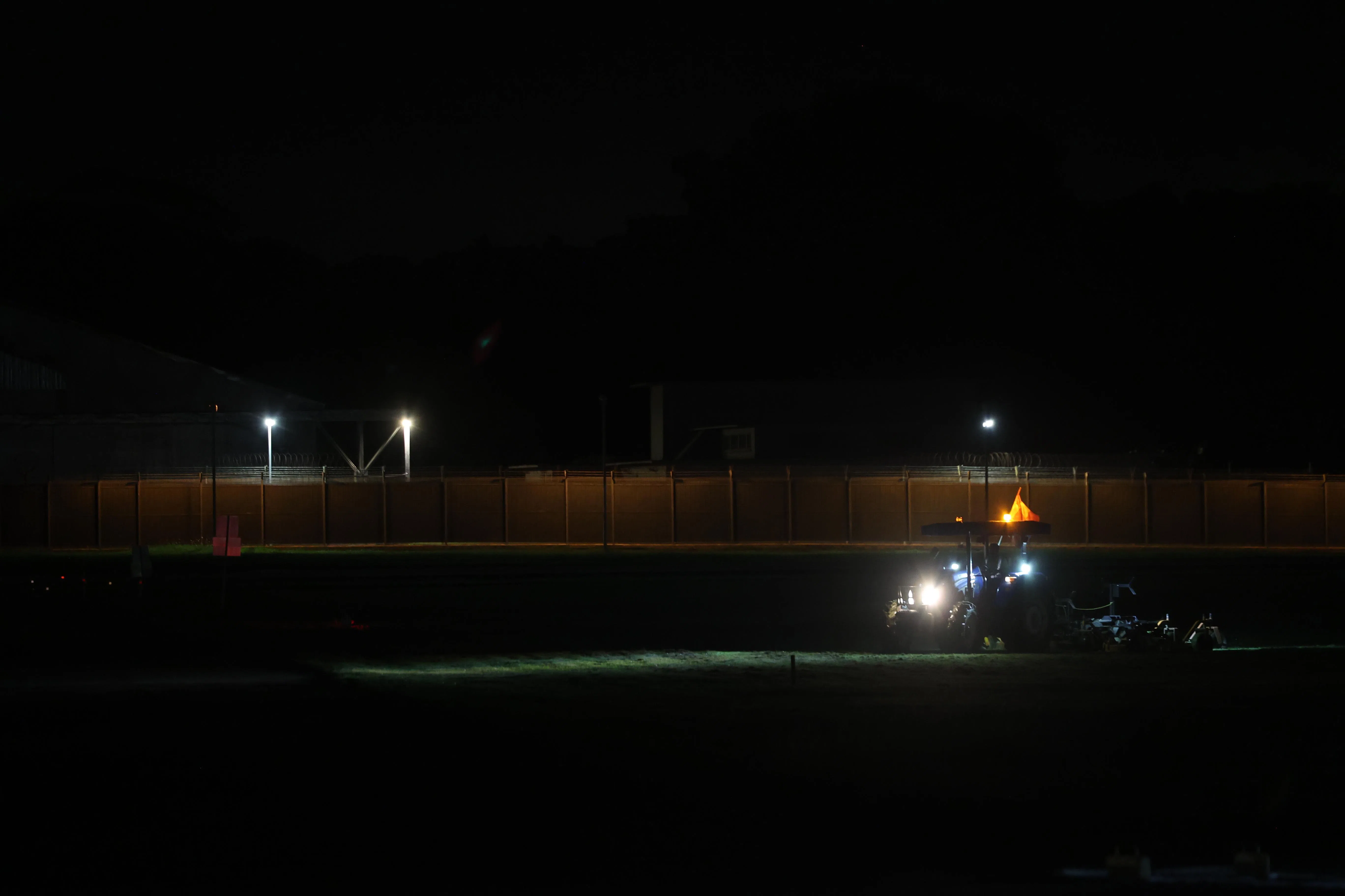 
维修人员在微弱的灯光下修剪跑道周围的杂草。（白艳琳摄）