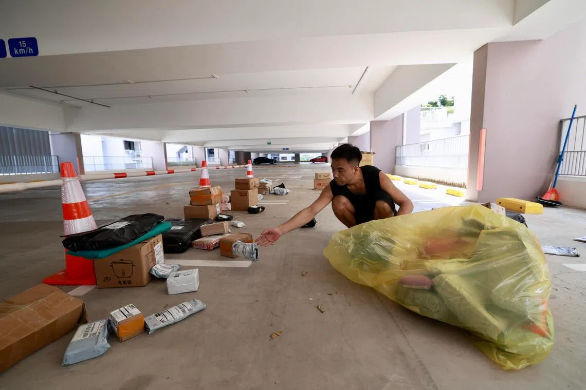 送货员葛龙在停车场，根据不同座组屋楼层进行最后一轮分拣，风雨无休。每送一个包裹，他能赚5角钱或6角钱。（陈斌勤摄）