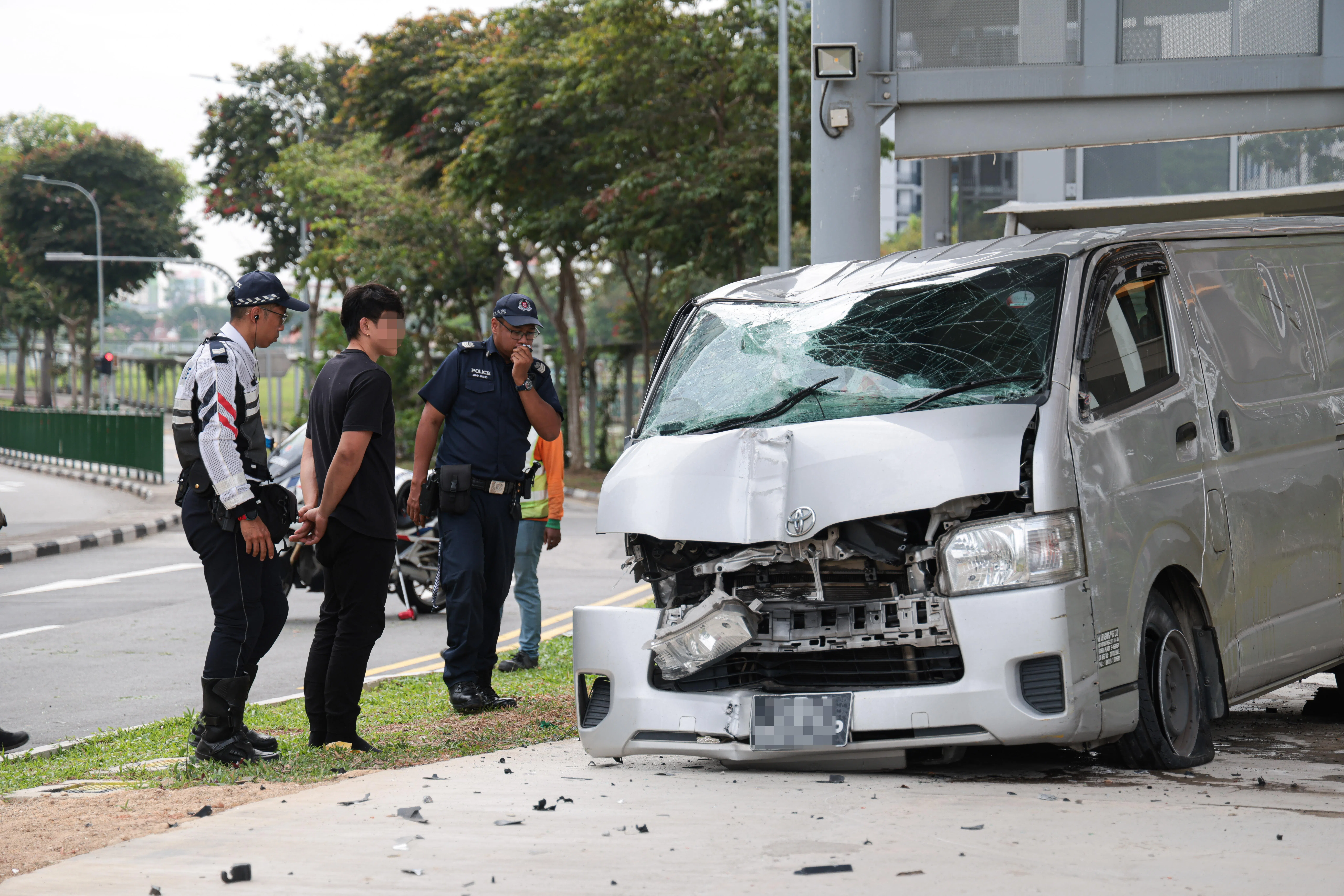 记者下午约3时抵达时，肇事司机（黑衣）正接受警方问话，据观察没有明显外伤。（李冠卫摄）