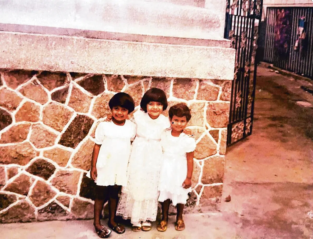 小时候的朱莱哈（中）跟亲人在学校门外合影，右侧铁闸门处就是胡先的住家。（朱莱哈提供）