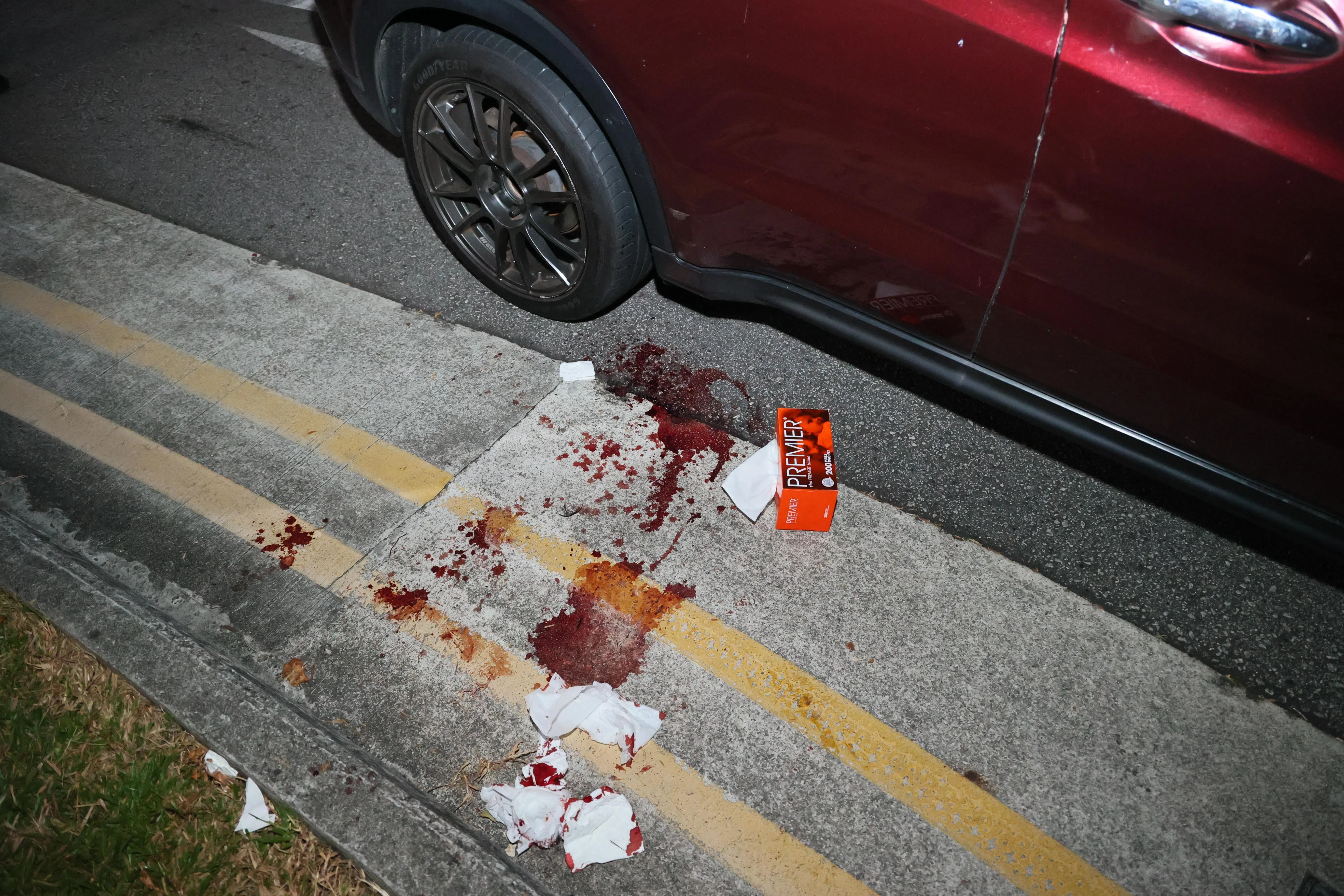 车子右侧后座门上有轻微撞击痕迹，地面上留有一摊血迹，以及沾血迹的盒装抽纸。（潘丰源摄）