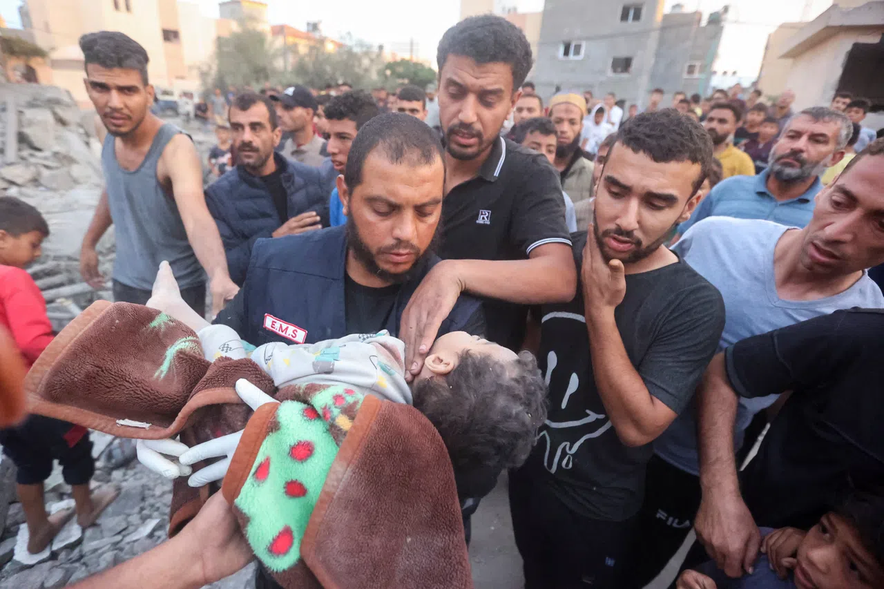 2023年10月17日，救援人员在加沙地带南部城镇康尤尼斯（Khan Younis）遭以色列空袭的废墟中抢救一名重伤的孩子。（路透社）