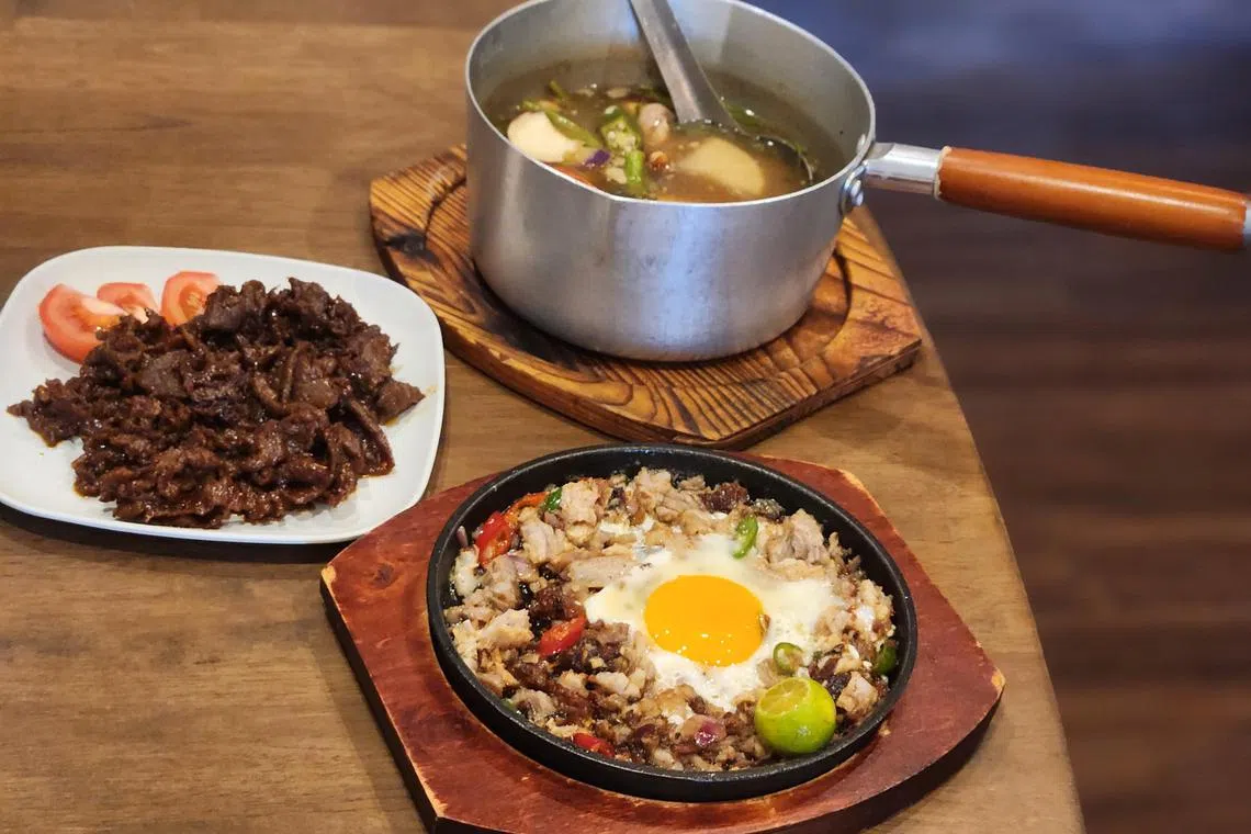 铁板牛油烧肉块（Sisig，前）、辣香炒牛肉（左）和烧肉蔬菜酸汤（Sinigang），都是菲律宾的地道风味。（陈爱薇摄）