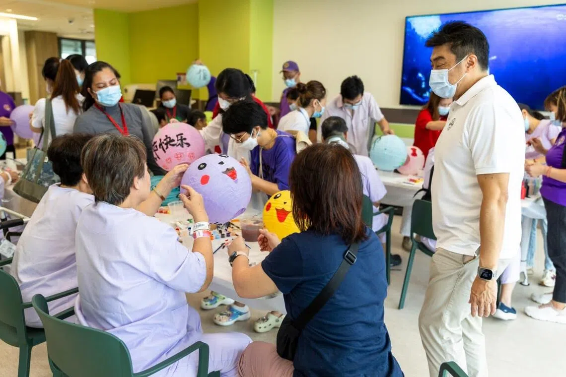 新加坡宗乡会馆联合总会约40位总会理事与义工，在8月17日和陈笃生医院的病患、家属和医院职工进行手绘灯笼活动，以300盏灯笼点缀医院通往诺维娜Square 2商场的天桥，为中秋节庆增添暖意。（新加坡宗乡联合总会提供）