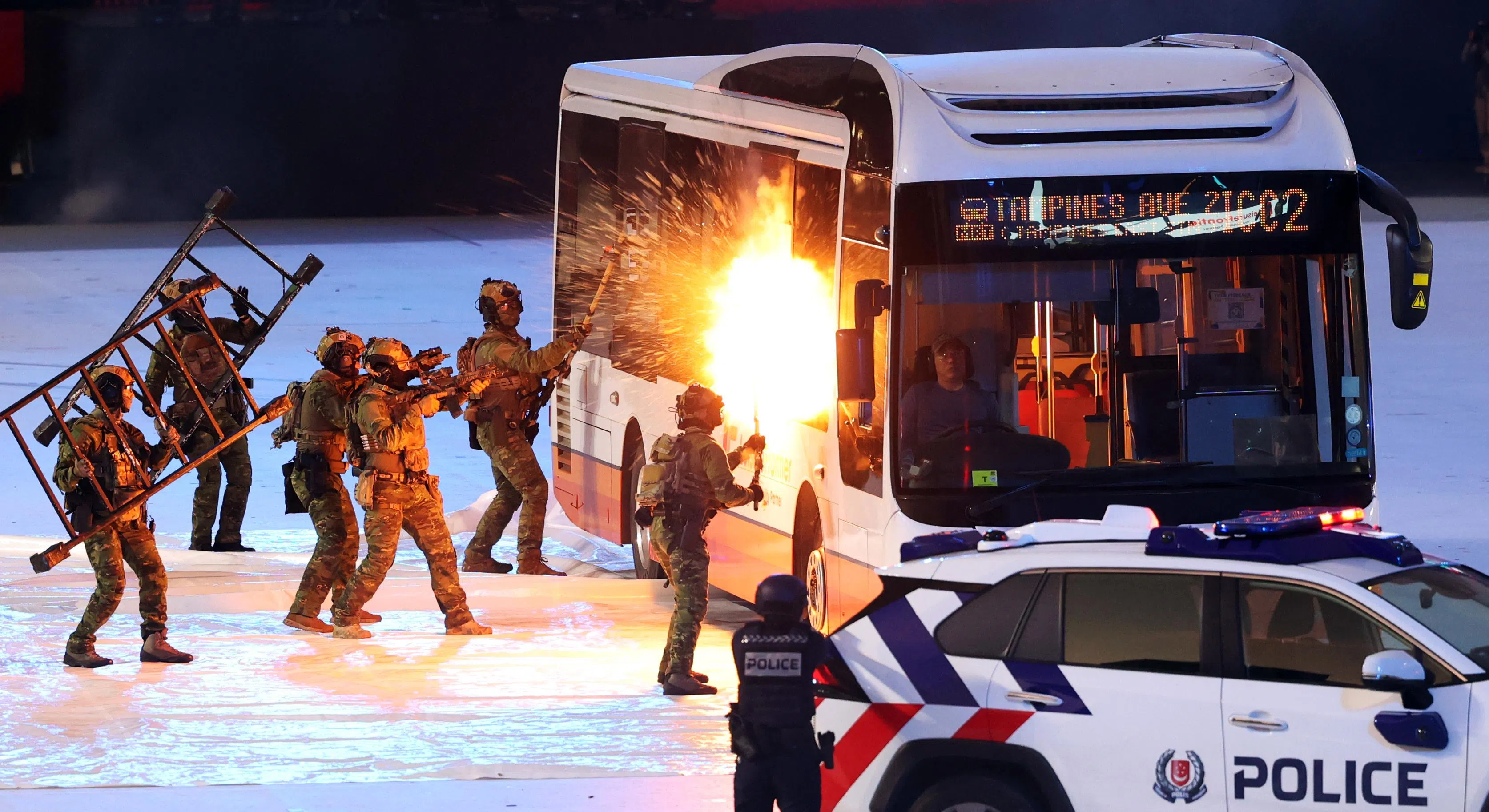 警方拦截一辆模拟遭劫持的巴士后，破窗进入解救人质。（唐家鸿摄）