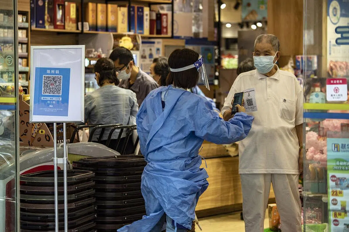 在上海，一名穿着防护服的工作人员在6月13日扫描一个客人的健康码。（彭博社）