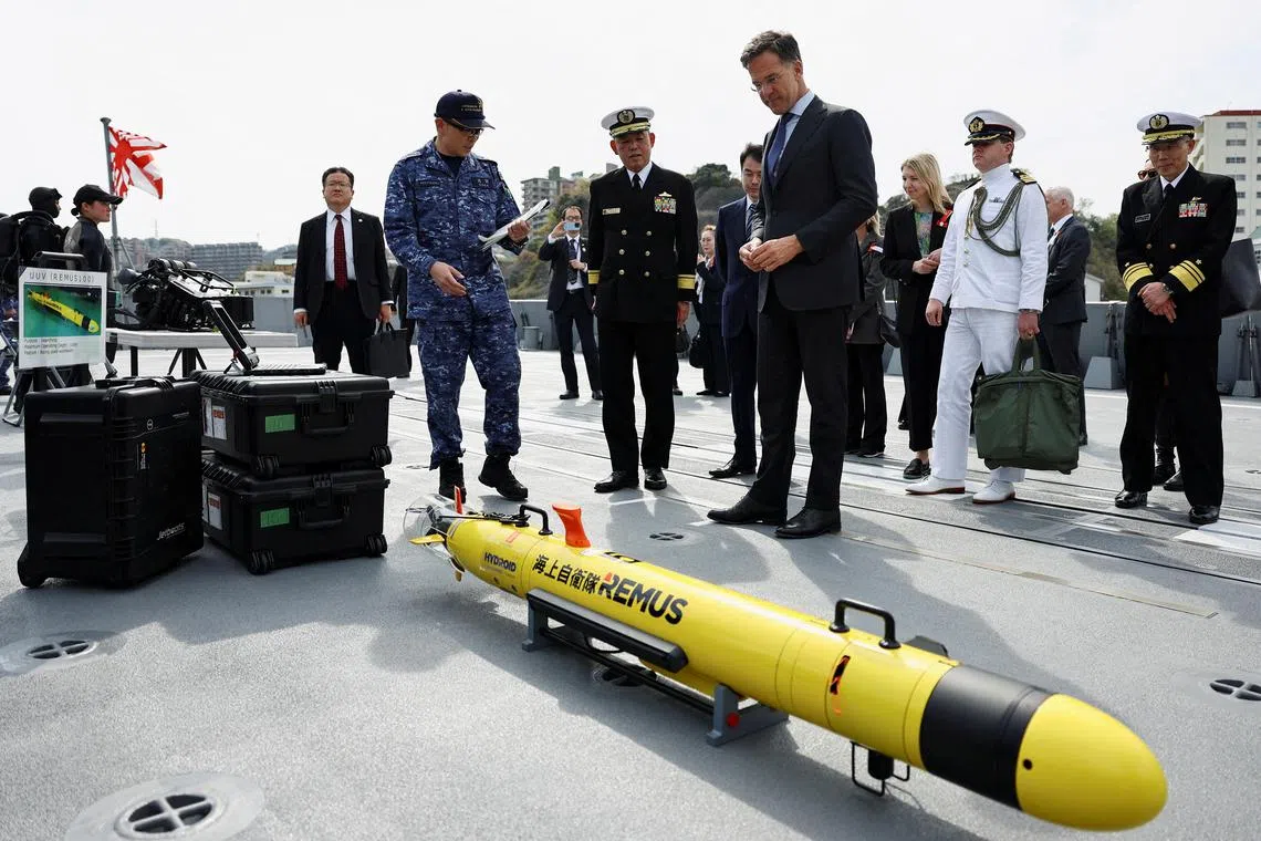 北约秘书长吕特（前排右一）周二在东京南部横须贺海军基地参观日本海上自卫队隐形护卫舰上的军事装备。（路透社）