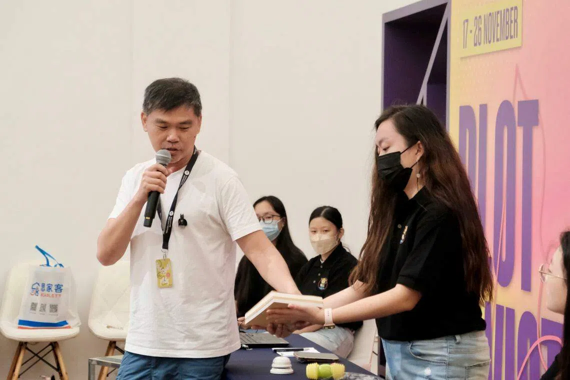 本地作家叶孝忠为大家介绍他向中国著名书籍设计师周晨拿到的作品《美编派》。（张菲扬摄）