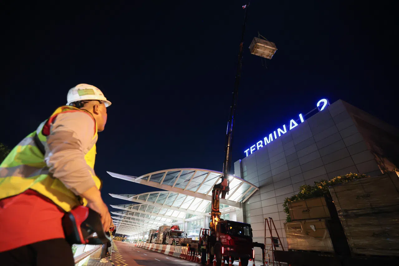 地面的起重机操控人员缓缓把装有太阳能板的箱子提到第二搭客大厦的顶层。（李冠卫摄）
