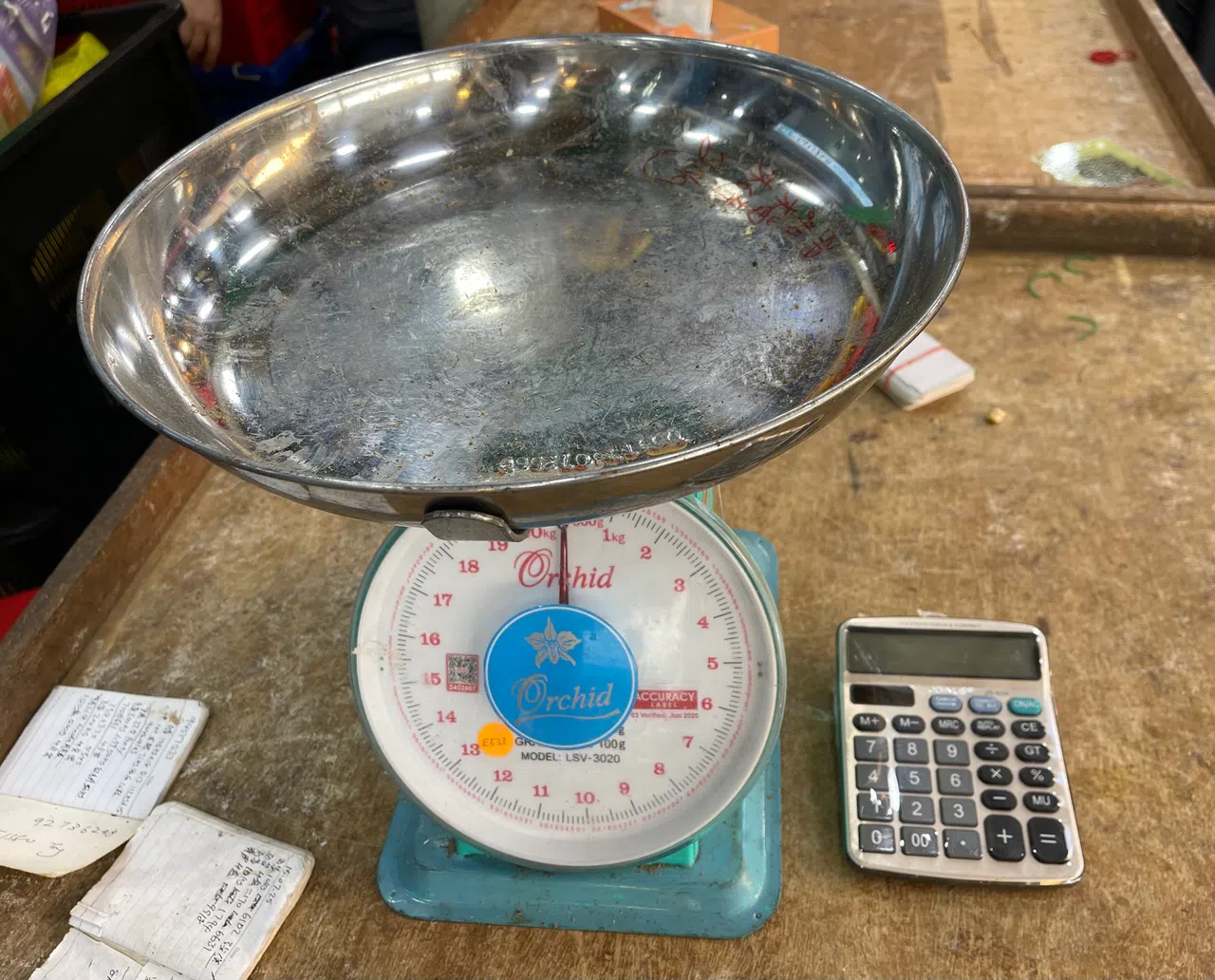 摊主指托盘秤刚送去保养过，经营十多年没被投诉过有称重的偏差。（余明飞摄）