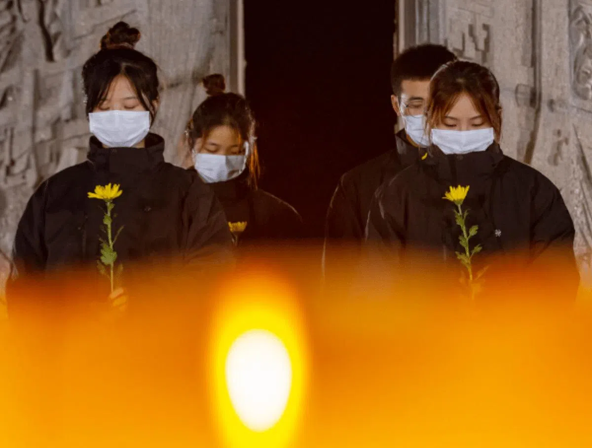 2022年12月12日晚，南京·和平之夜，接力诵读的青年胸口佩戴紫金草徽章。（新华社）