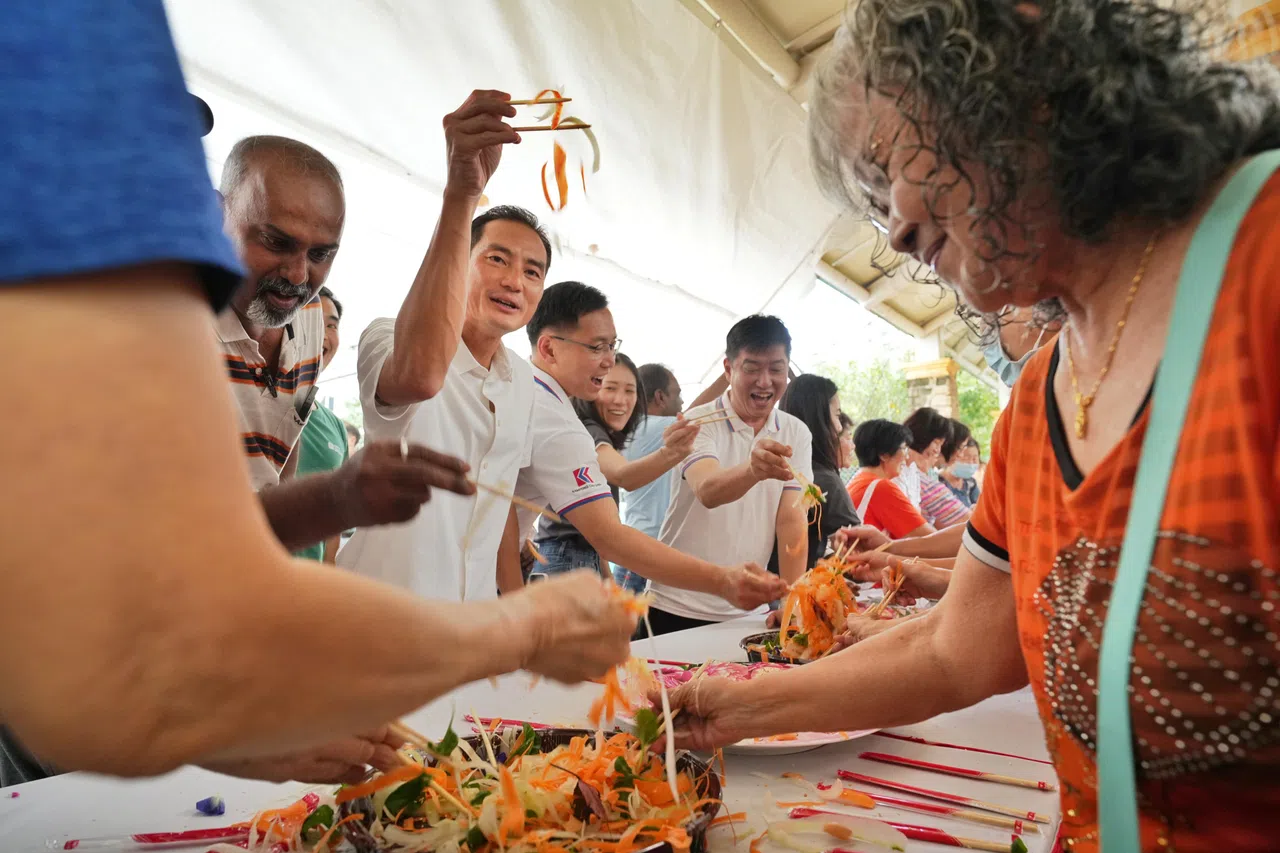 数码发展及新闻部兼国家发展部高级政务部长陈杰豪（左二）星期六出席新社区中心推介活动，与居民一起捞鱼生。（谢智扬摄）
