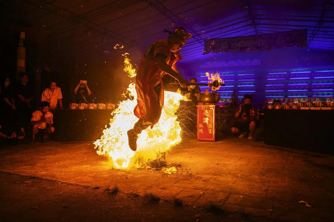 喃呒师傅腾身跃过火焰，寓意从地狱中解救亡灵。（龙国雄摄）