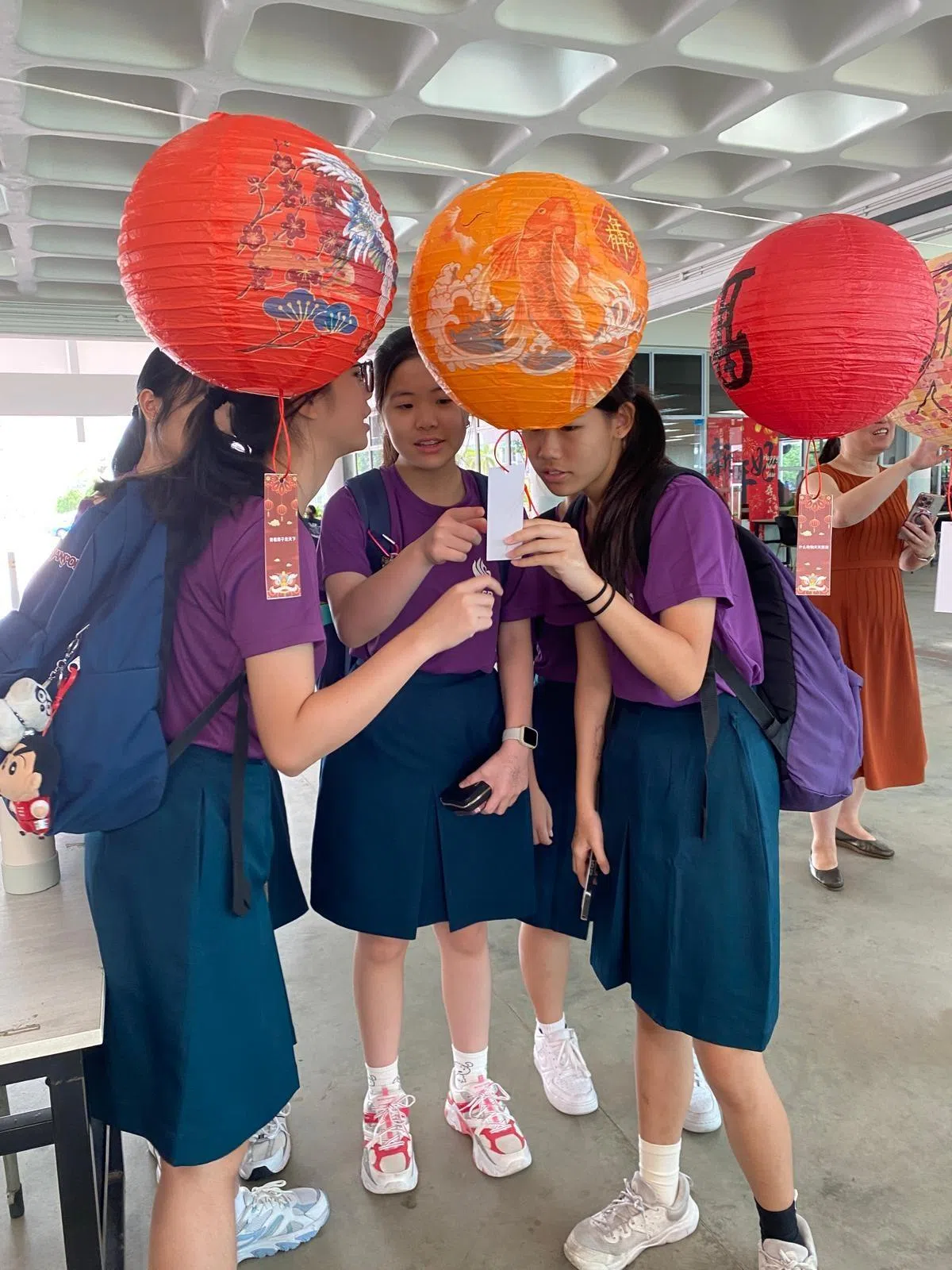 学生在挂满红灯笼的摊位前参与猜灯谜活动，在趣味互动中，深化对母族文化的认识。（安德逊实龙岗初院提供）