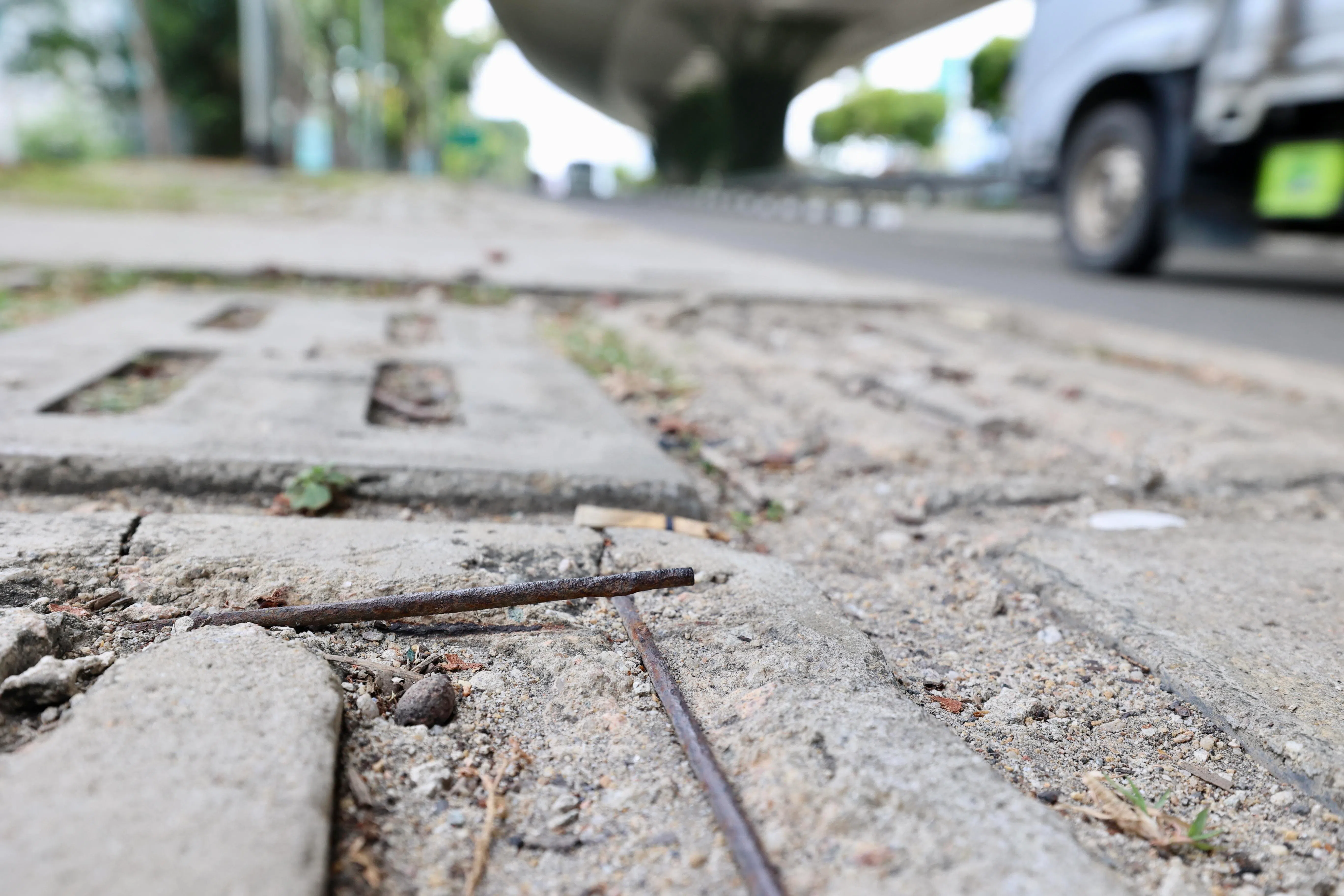 由于路砖表面的水泥脱落，导致内部钢筋暴露在外；客工或是在准备穿越马路时，不小心踩中微微翘起的钢筋。（邝启聪摄）