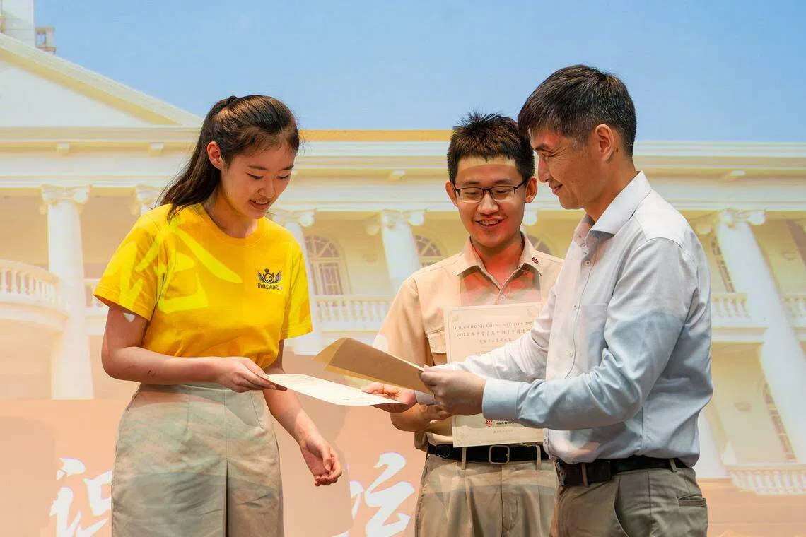 陈刚博士（右）颁发获奖证书给华中高一学生佘玥欣（左）和盖乙丞（中）。（华侨中学提供）