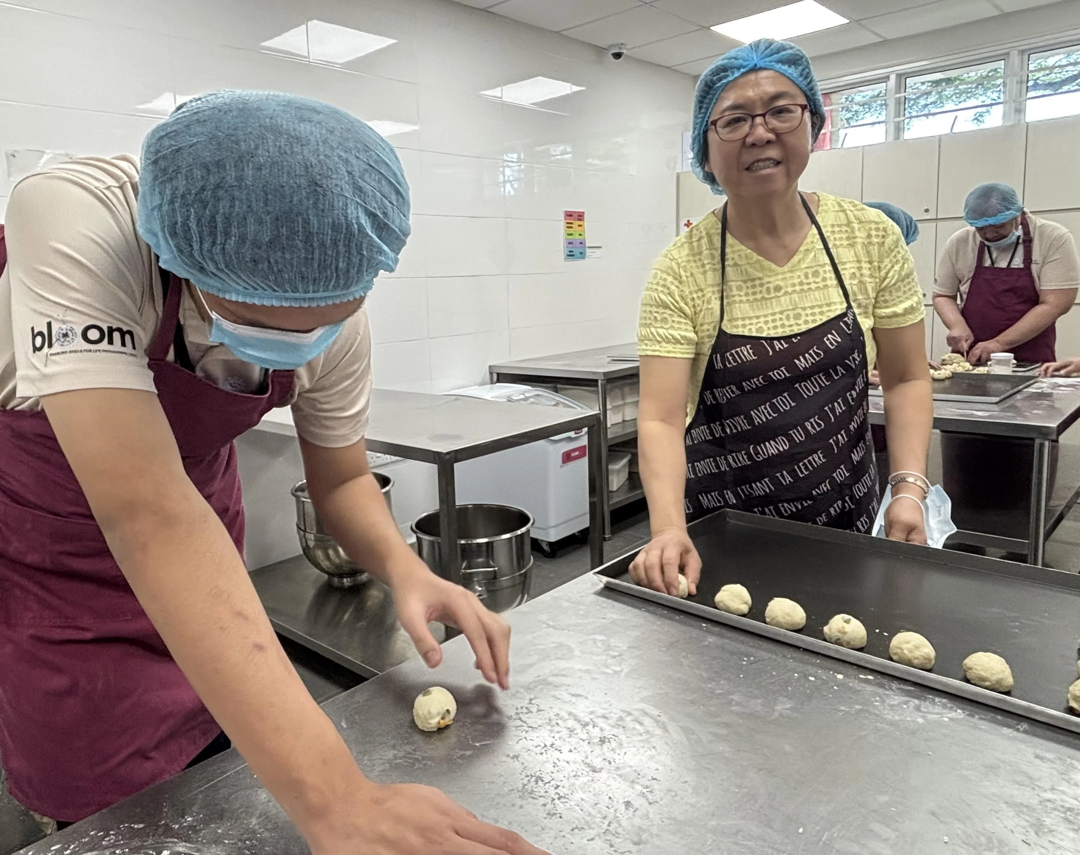 郑云嫦（右）对烘焙感兴趣，她充当培训导师的“另一双眼”，帮忙导师观察学员进度，引导他们进行烘焙工作。（胡洁梅摄）