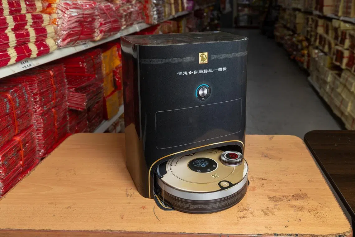 拖地机器人印有“智能全自动扫地一体机”、“按键尘盒”，以及拖地时间等字眼，售价12元8角。（吴先邦摄）