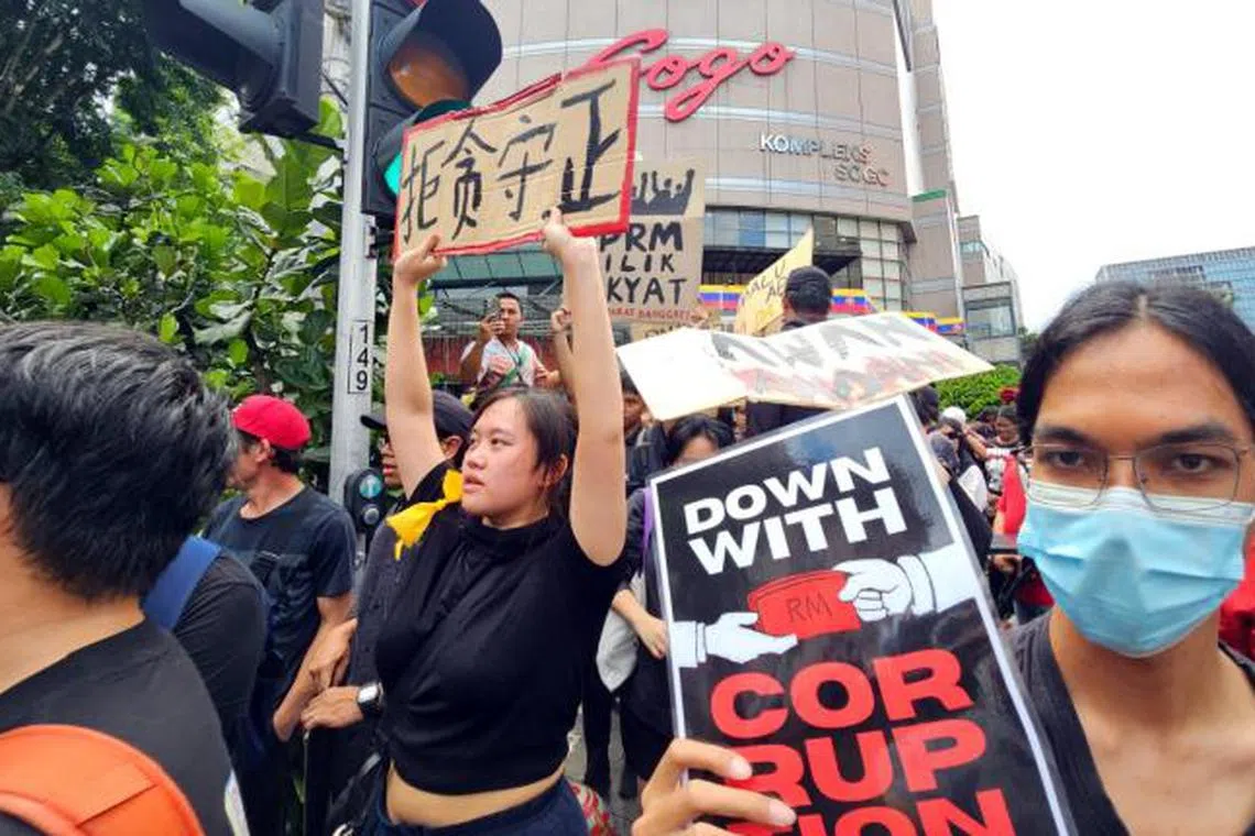 马来西亚各族青年积极响应集会主办方的号召，其中一名华族集会者高举“拒贪守正”的纸牌，表达对抗贪腐的决心。（南洋商报）