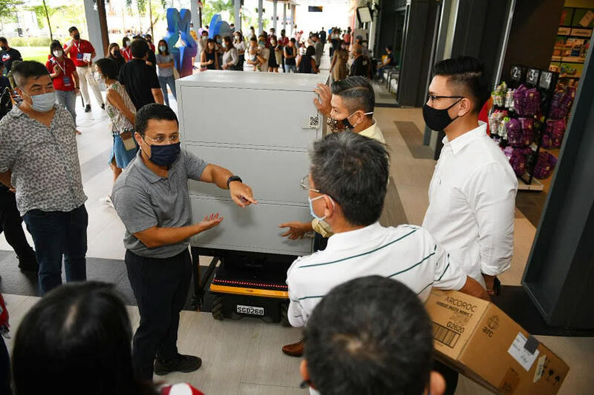 国家发展部长李智陞（左二）参观新开幕的榜鹅北岸广场时，了解业者如何在送货机器人的帮助下，把货车卸下的物品送到店里。（特约陈佳誉摄）