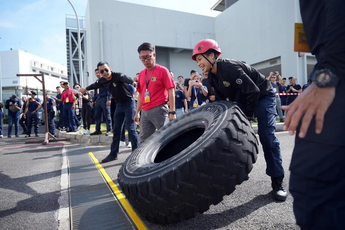 特勤挑战赛最后环节，女参赛者须将80公斤的轮胎翻到终点线，并敲响一旁的钟才算完成比赛。（谢智扬摄）