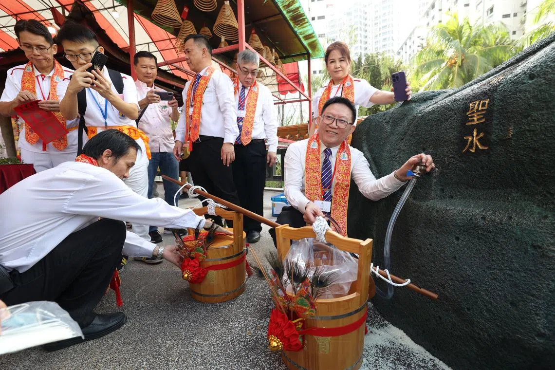 普救善堂总理林怡丰（右一）在安济圣王庙前取水。（郑一鸣摄）