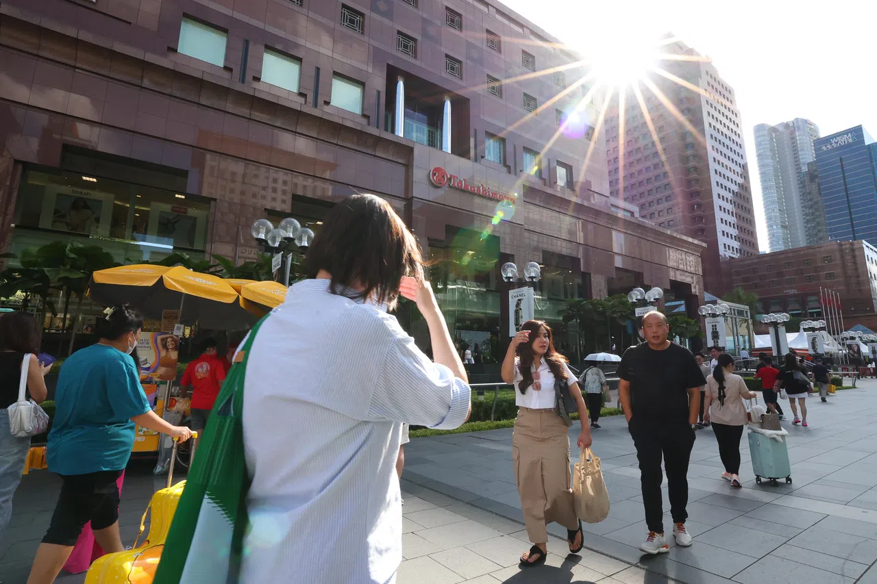 近来烈日当空，人们在义安城高岛屋百货公司外行走时，不禁用手遮挡刺眼的阳光。（林明顺摄）
