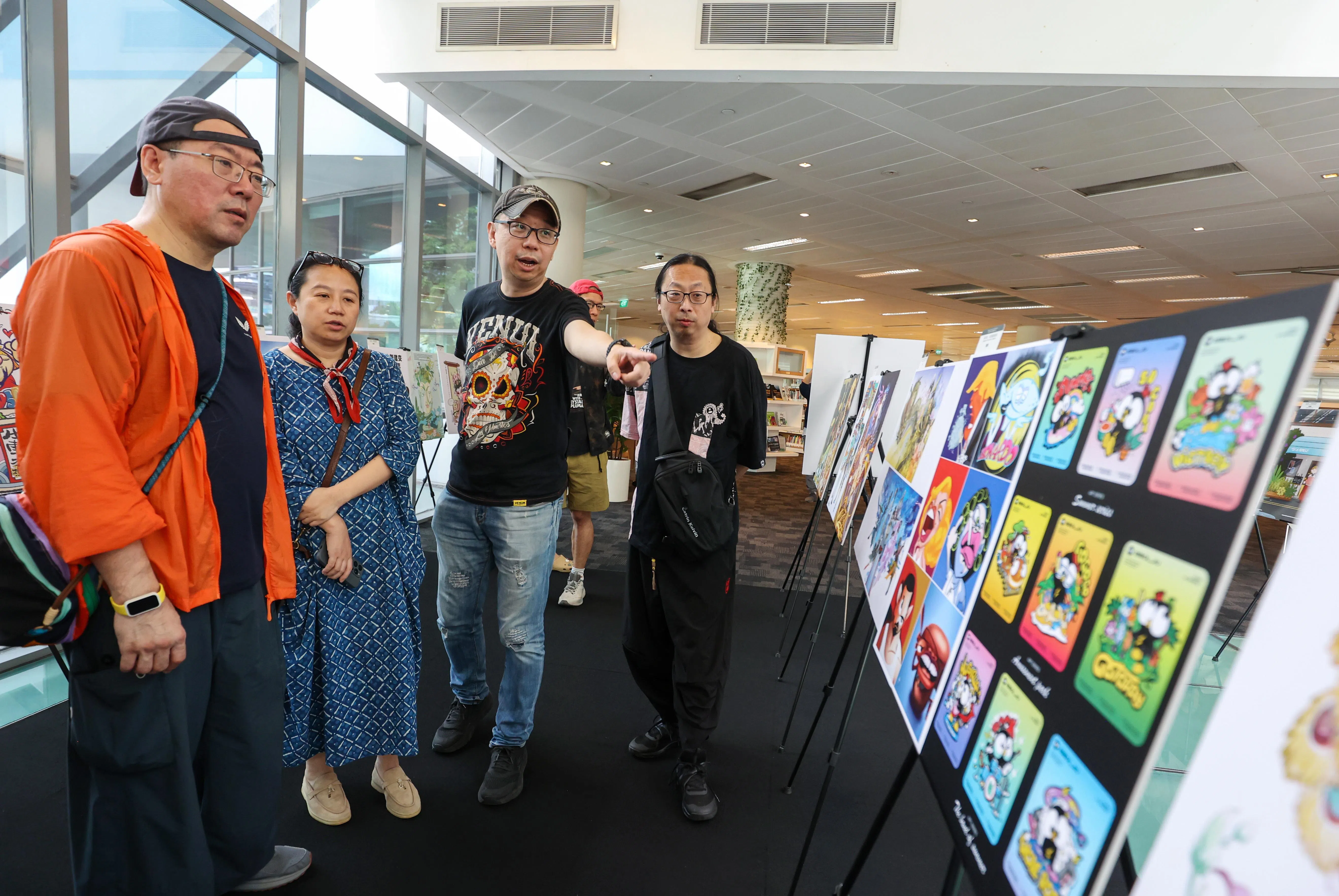 为庆祝新中建交35周年，“新加坡－中国漫画联展”在裕廊图书馆举行，展出鱼尾狮与石狮子、滨海湾金沙酒店与故宫天坛等融合两地文化符号的作品。（游甯稀摄）