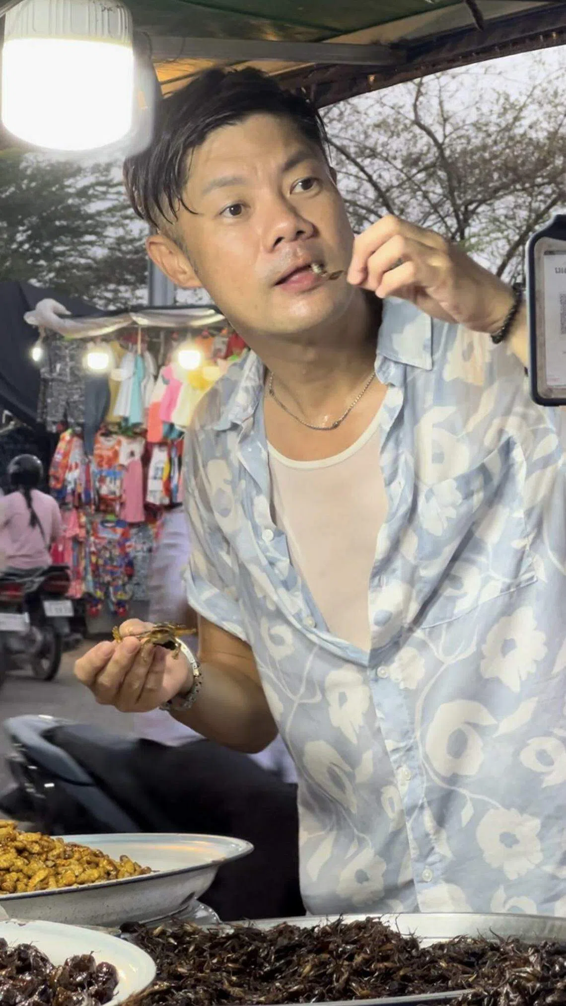 杨君伟在柬埔寨街边吃炸昆虫，结果泻肚子。（堂堂映画提供）