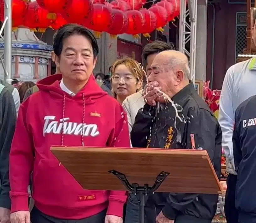 台湾总统赖清德（左）大年初二到台南发福袋，在听立委致辞时，庙宇主委林培火（右）身体不适呕吐，呕吐物也溅到赖清德左边手臂和衣物。（自由时报视频截图）