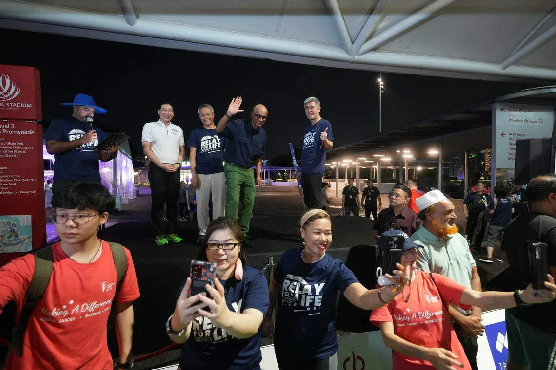 参与新加坡防癌协会“为生命接力”义跑的公众在舞台下与尚达曼总统（台上右二）和嘉宾们“自拍”；台上左二起为新加坡防癌协会首席执行官钟良兴 、“为生命接力”筹委会主席麦豪杰和新加坡防癌协会主席李明德 。（谢智扬摄）