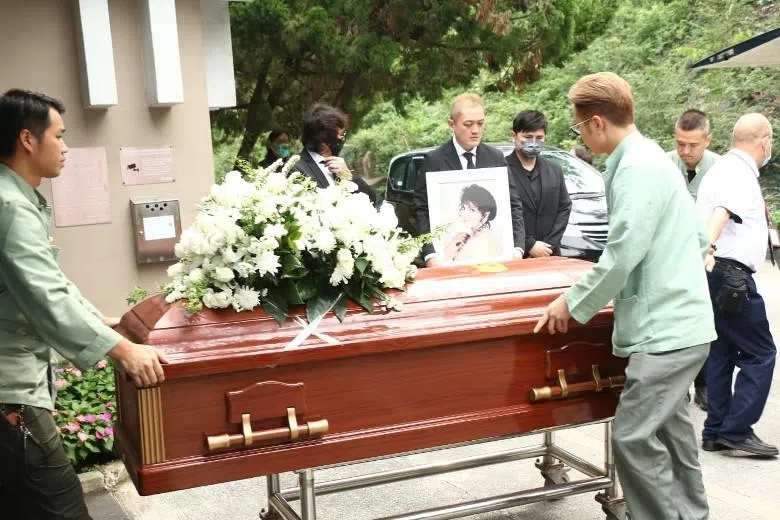 李泳汉捧着母亲的遗照，李泳豪陪伴在侧。（互联网）