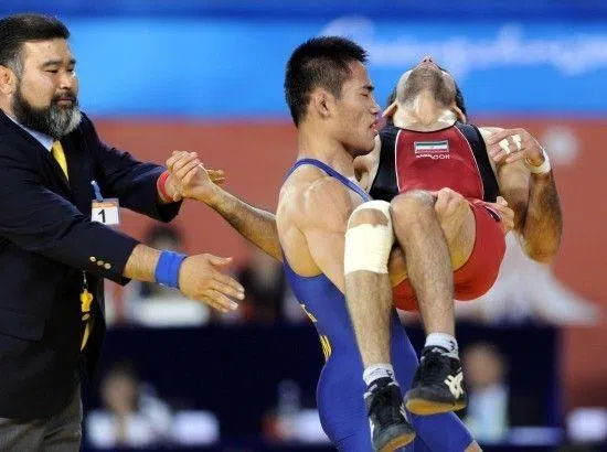 中国摔跤手高峰（蓝衣）抱起对手扎林科拉伊下台。（互联网）