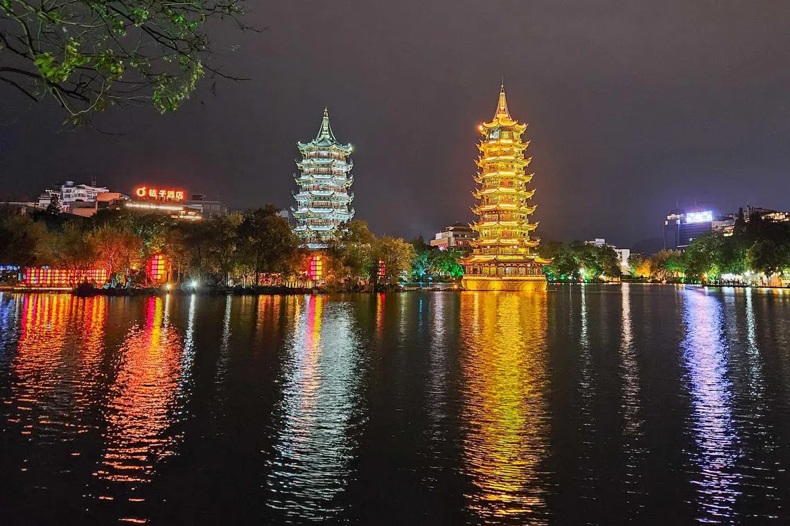 日月双塔在灯光下愈加神秘，倒影在湖水中轻轻摇曳，宛如置身人间仙境。（客桑摄）