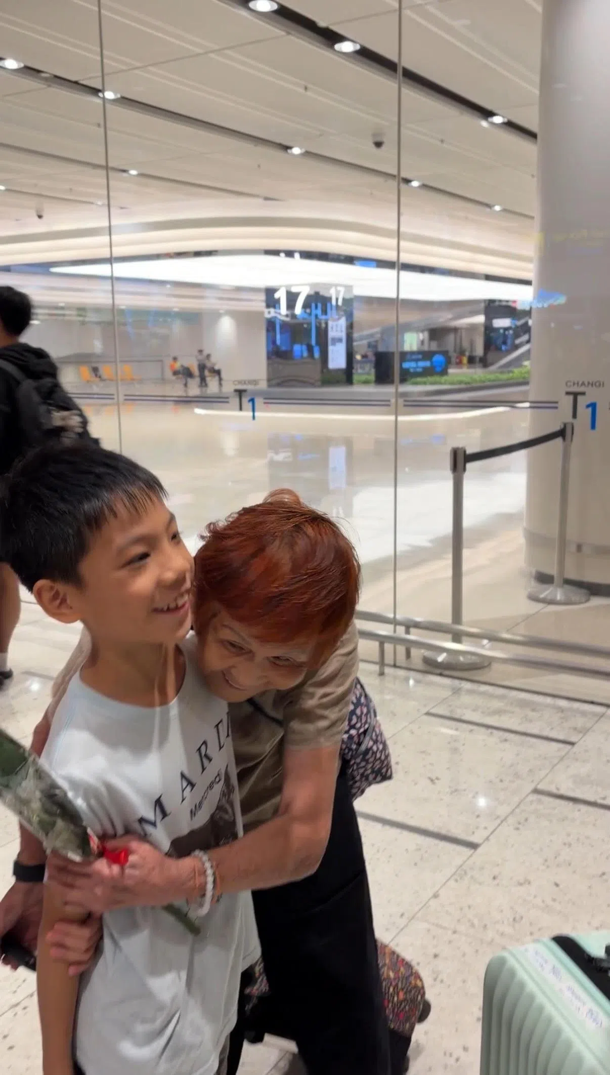 卓家亲戚当中的另一位82岁奶奶走出抵境厅后，也与孙子紧紧相拥。（董柏汝摄）