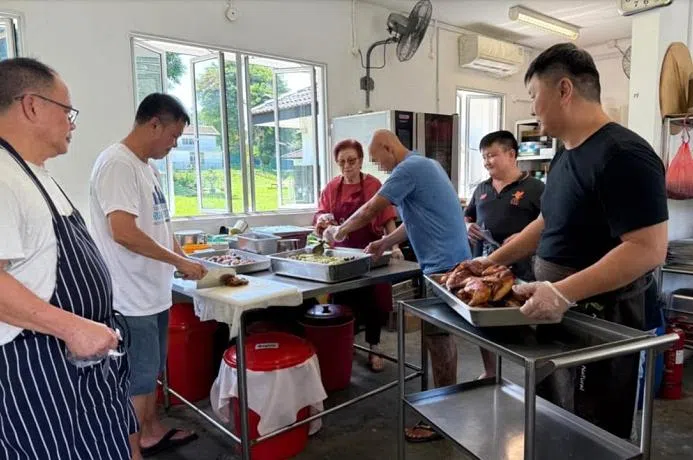 突破村庄主厨陈明裕（右一） 指导吴金宝（左一）和卓鸿龙（左二）等学员烹煮红烧鸡肉。（突破宣道之家提供）