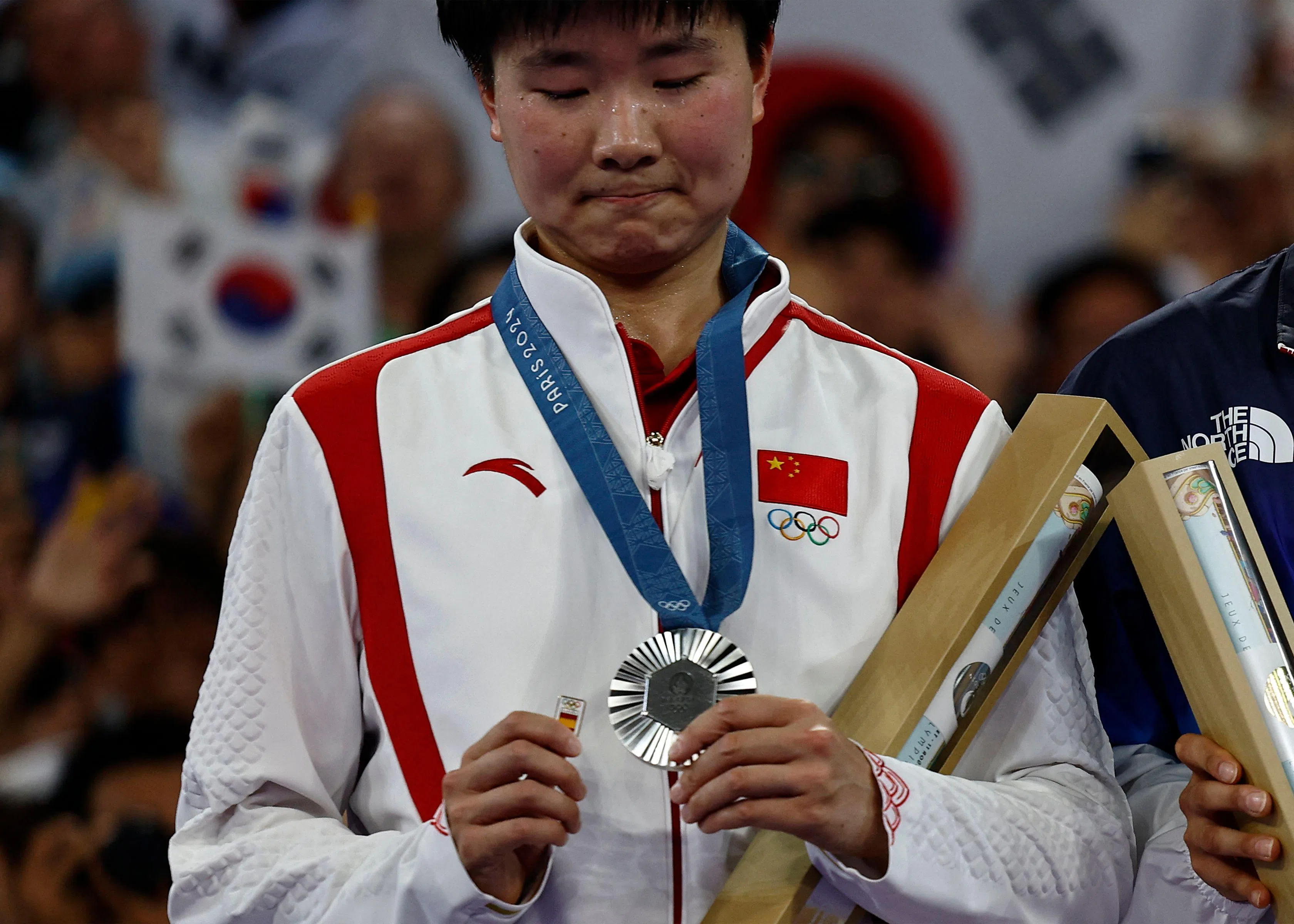 拿着西班牙徽章上台领奖，中国女将何冰娇的善良举动被各大媒体报道。（法新社）