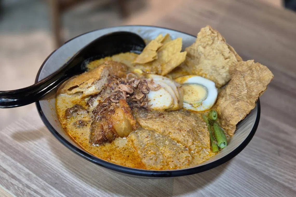 Kangji Curry Mee的招牌咖喱面有招牌脆皮烧肉、猪皮、炸云吞、鸡蛋和豆卜等配料。（陈爱薇摄）