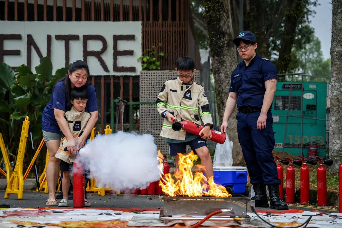 活动现场设立的模拟灭火展位吸引不少居民亲自上阵，学习如何正确灭火。（叶振忠摄）