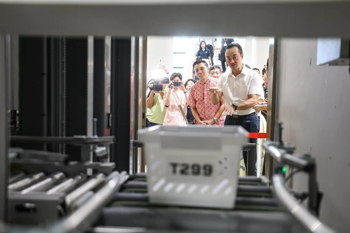 卫生部兼人力部高级政务部长许宝琨医生（右一）及交通部代部长兼财政部高级政务部长、蔡厝港集选区议员萧振祥（右二），了解自动输送药物系统如何运作。（关俊威摄）